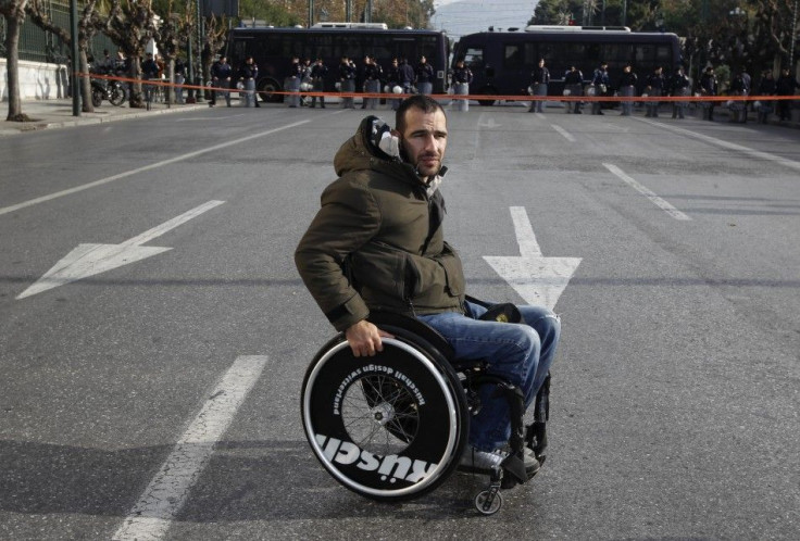 A protester with disabilities is seen in front of a police formation during a protest against austerity measures in Athens