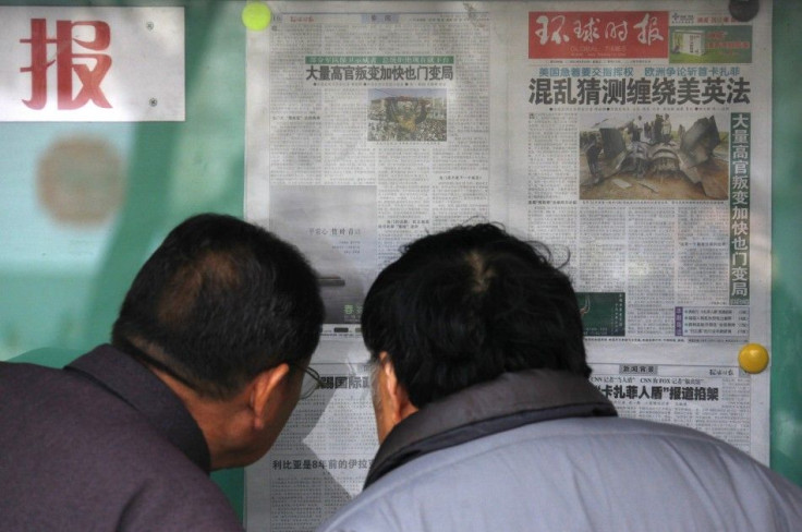 Locals read Chinese newspapers displayed on a public notice board in central Beijing