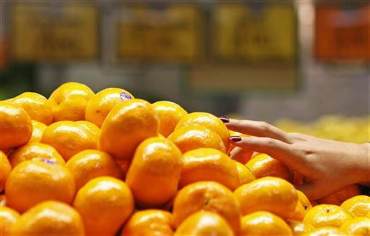 A woman picks up some mandarin oranges at a fruit shop