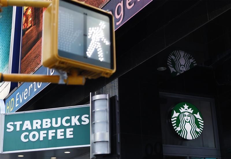 A walk sign flashes in Times Square in front of a store bearing the new Starbucks logo in New York