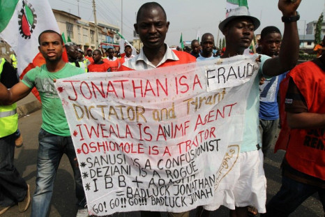 A man holds a banner as protesters march through a road on the third day of a protest against a removal of fuel subsidies in Lagos