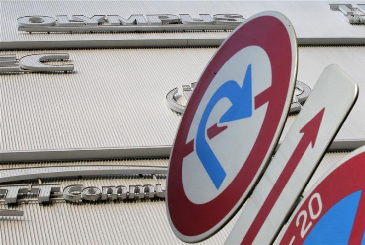 The logo of Olympus is seen behind traffic signs outside an electronic shop in Tokyo