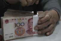 An employee seals a stack of yuan banknotes at a branch of Industrial and Commercial Bank of China in Huaibei