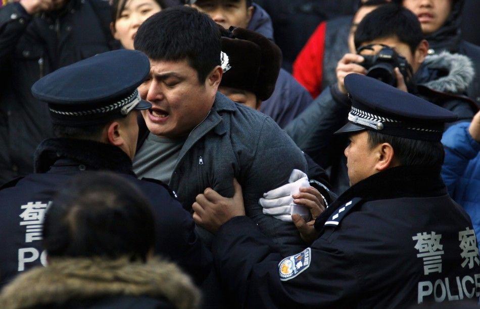 A man is dragged away by police after he refused to leave from the front of the Apple store in the Beijing district of Sanlitun