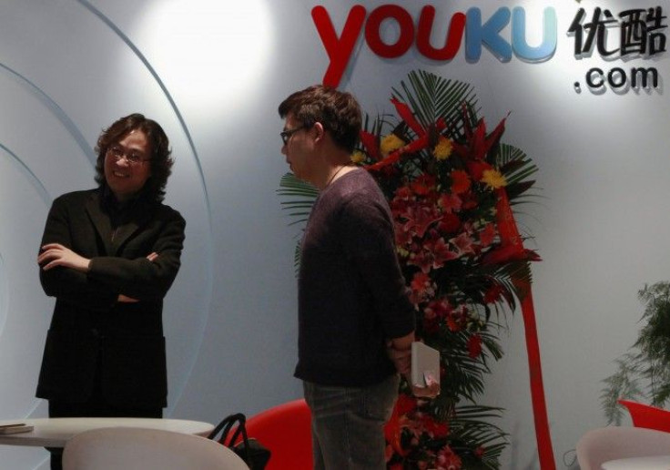A client speaks to an employee next to the logo of Youku.com at the company's headquarters in Beijing