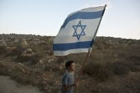 A Jewish youth holds an Israeli flag during a rally march outside the West Bank settlement of Itamar, near Nablus