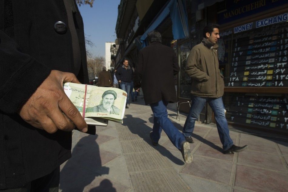 A money changer holds Iranian rial banknotes as he waits for customers in Tehran