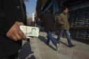 A money changer holds Iranian rial banknotes as he waits for customers in Tehran's business district January 7, 2012.
