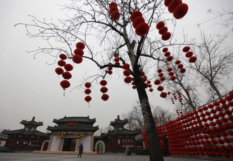 A woman walks past red lantern decorations for the upcoming temple fair at an entrance of Longtan park in Beijing