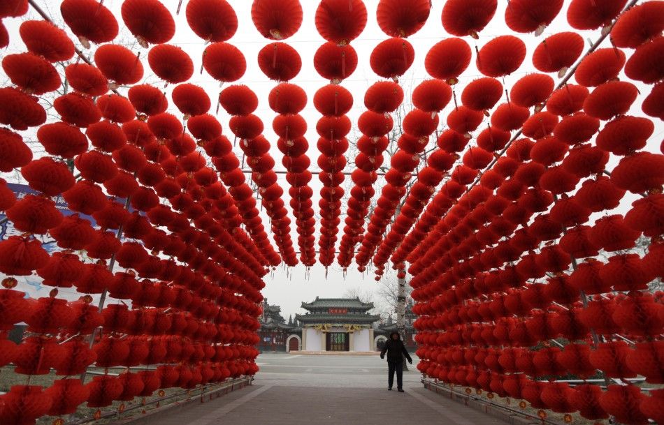 A woman walks past red lanterns, which were put up as decoration for an upcoming temple fair, at an entrance of Longtan park in Beijing