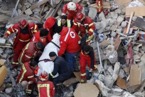 Lebanese Red Cross and Civil Defence personnel transport a dead body found under the debris of a collapsed building in Beirut