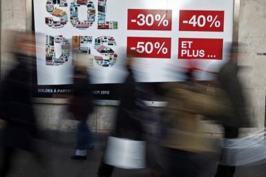 Shoppers walk past a clothing store window advertising sales during the first day of the winter sales in Nice