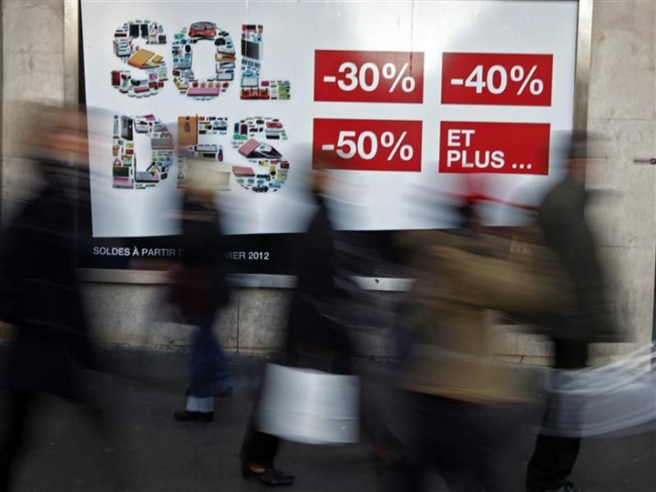 Shoppers walk past a clothing store window advertising sales during the first day of the winter sales in Nice