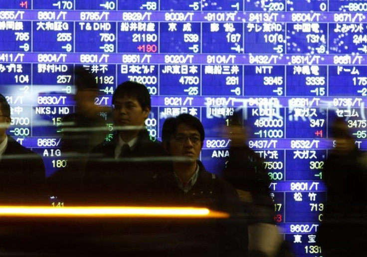 Passers-by walk in front of a stock quotation board in Tokyo