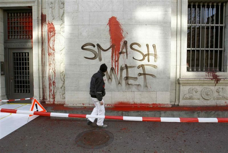 A worker of a cleaning company stands in front graffiti reading 'Smash WEF' on the facade of the Swiss National Bank's building in Zurich