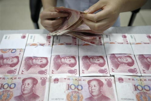 An employee counts yuan banknotes at a bank in Huaibei