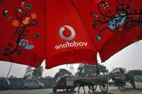 Men ride their horse carts past an umbrella with a Vodafone logo on a road in Jammu November 21, 2011.
