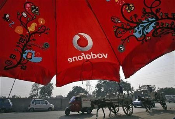 Men ride their horse carts past an umbrella with a Vodafone logo on a road in Jammu November 21, 2011.