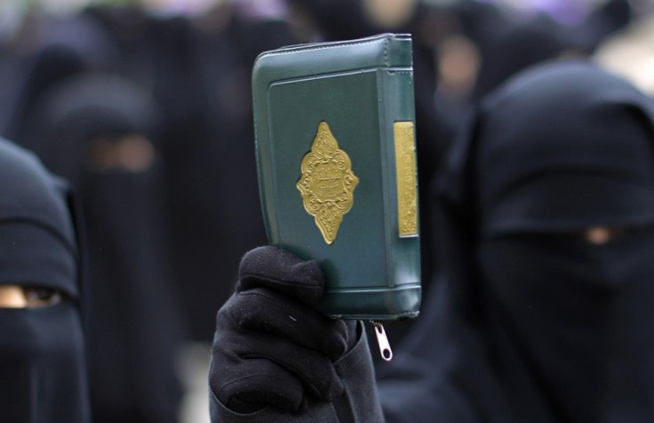 A woman holds up a copy of the Koran