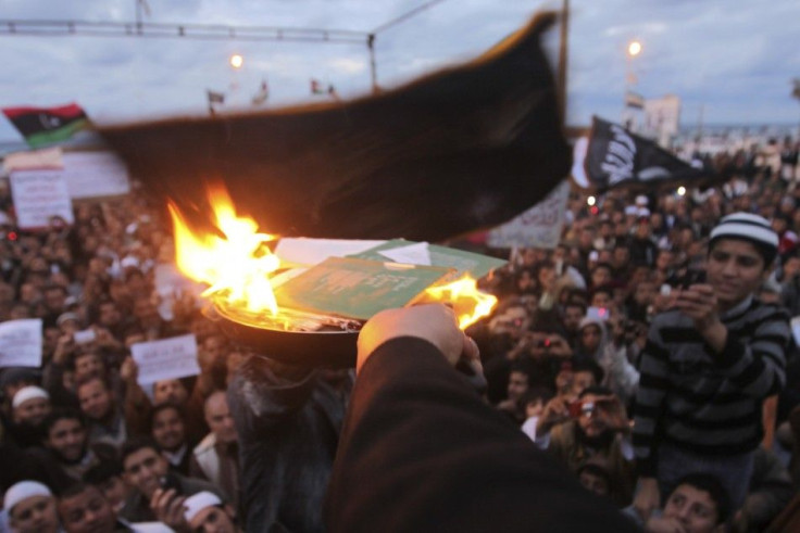 People burn copies of the &quot;Green Book,&quot; Muammar Gaddafi's eccentric handbook on politics, economics and everyday life, and pictures of Muammar Gaddafi during a demonstration demanding the Libyan National Transitional Council apply Islamic s