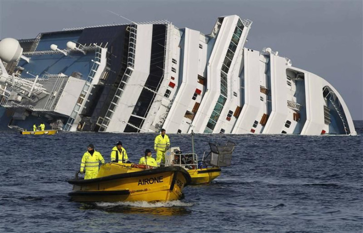 Oil recovery workers pass the Costa Concordia cruise ship