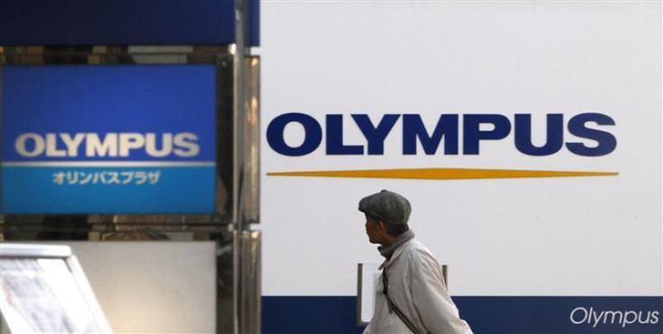 A man walks past signboards of Olympus Corp outside its showroom in Tokyo