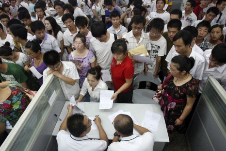 Jobseekers pass their resumes to representatives from Foxconn at a job fair in Zhengzhou