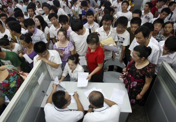 Jobseekers pass their resumes to representatives from Foxconn at a job fair in Zhengzhou