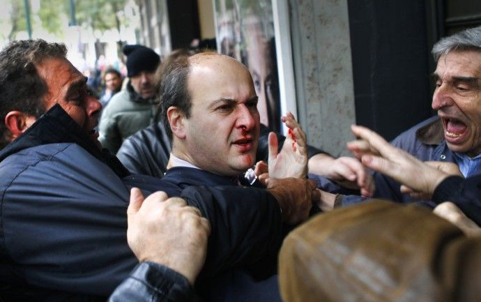 Former conservative minister Kostis Hatzidakis reacts after being attacked by leftists with their fists, stones and sticks, while they shouted: "Thieves! Shame on you!" during a march against austerity measures in central Athens