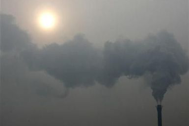 A chimney billows smoke as the sun shines through haze on a cold winter&#039;s day in Beijing December 24, 2009.