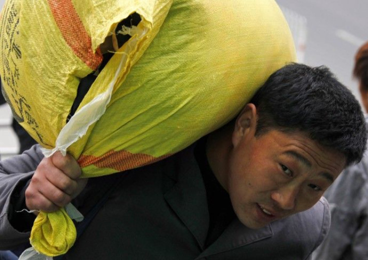 A migrant worker carries his belongings on his shoulder as he walks to a train station in Beijing October 19, 2010. China must lift the incomes and spending power of hundreds of millions of workers and farmers to keep the world's second-biggest economy fr