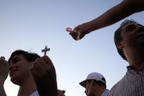 A protester shows a pilgrim a condom who in turn shows him a cross during a demonstration against what they claim is the expensive cost of the papal visit in central Madrid coinciding with the second day of the World Youth Day meeting