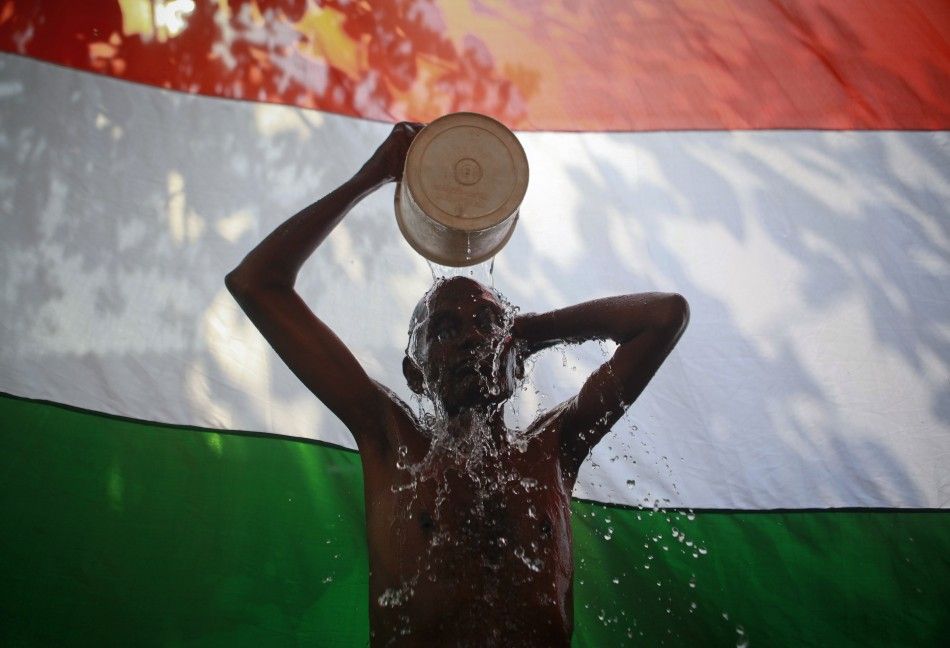 A man takes a bath outside his shanty in front of the Indian national flag in Dharavi, one of Asias largest slums, in Mumbai