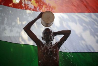 A man takes a bath outside his shanty in front of the Indian national flag in Dharavi, one of Asia's largest slums, in Mumbai