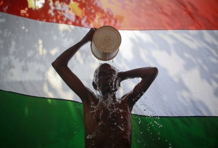 A man takes a bath outside his shanty in front of the Indian national flag in Dharavi, one of Asia's largest slums, in Mumbai