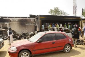 People stand in front of a police headquarters after a bomb attack in Nigeria's northern city of Kano January 21, 2012.