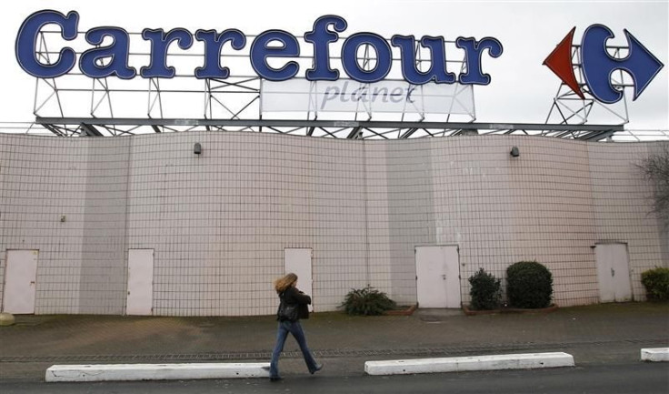 A woman walks below the logo of Carrefour Planet supermarket in Bordeaux