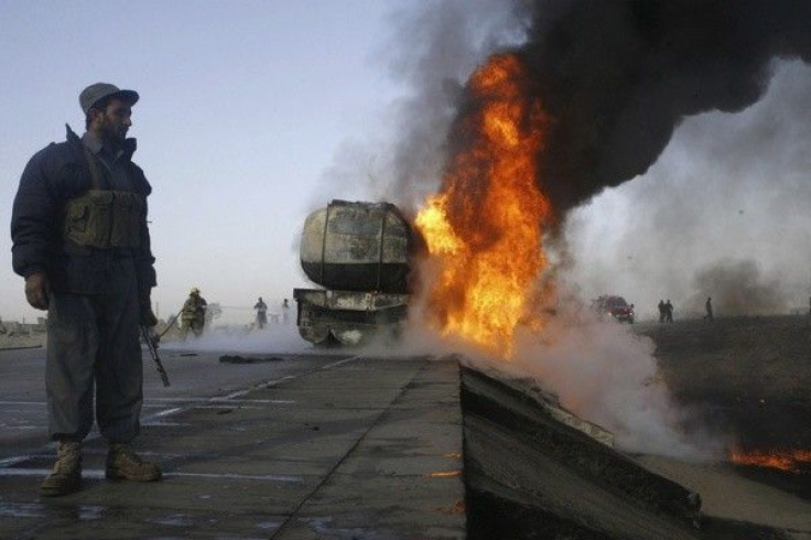 An Afghan policeman keeps watch next to a burning truck carrying fuel for NATO forces in Behsud district of Nangarhar province December 16, 2010. 