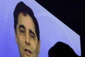A videographer is silhouetted in front of a video presentation featuring FCC Chairman Julius Genachowski during the International CTIA Wireless trade show in Las Vegas
