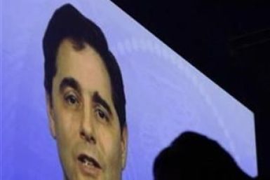 A videographer is silhouetted in front of a video presentation featuring FCC Chairman Julius Genachowski during the International CTIA Wireless trade show in Las Vegas