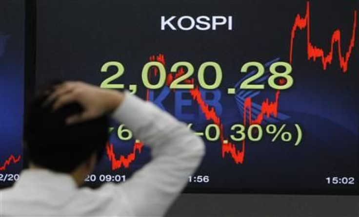 A foreign currency dealer walks past a screen displaying the Korea Composite Stock Price Index (KOSPI) at a bank in Seoul