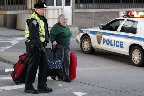 A police officer helps a woman with her luggage after informing her that Terminal A had been shut down by police at Newark Liberty Airport in Newark, New Jersey December 20, 2010.