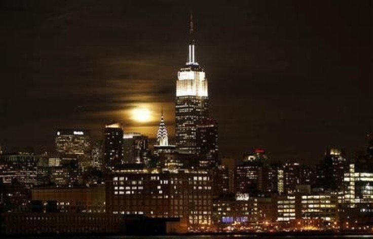 A full moon rises behind the Empire State Building and the Chrysler Building over the skyline of Manhattan in New York