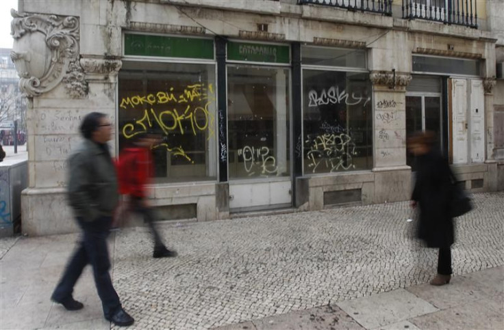 People walk near a closed down shop in downtown Lisbon