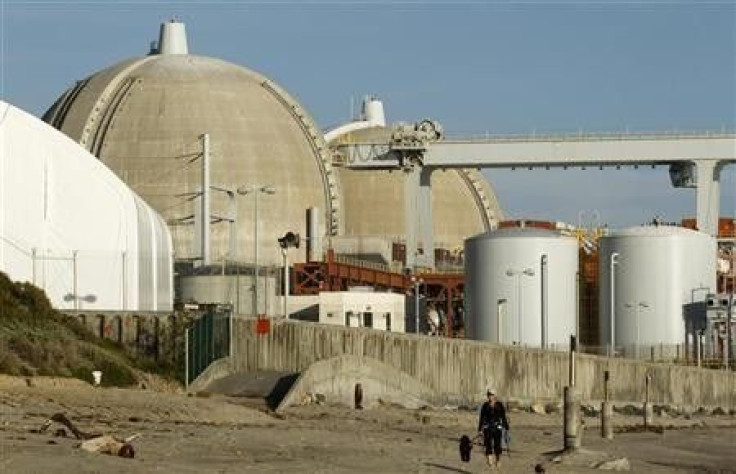 A woman and her dogs walk past the San Onofre Nuclear Generating Station that sits on the shore of the Pacific Ocean in North San Diego County, California