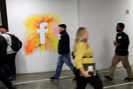 Employees walk past the company logo at the new headquarters of Facebook in Menlo Park
