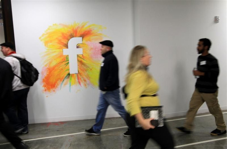 Employees walk past the company logo at the new headquarters of Facebook in Menlo Park