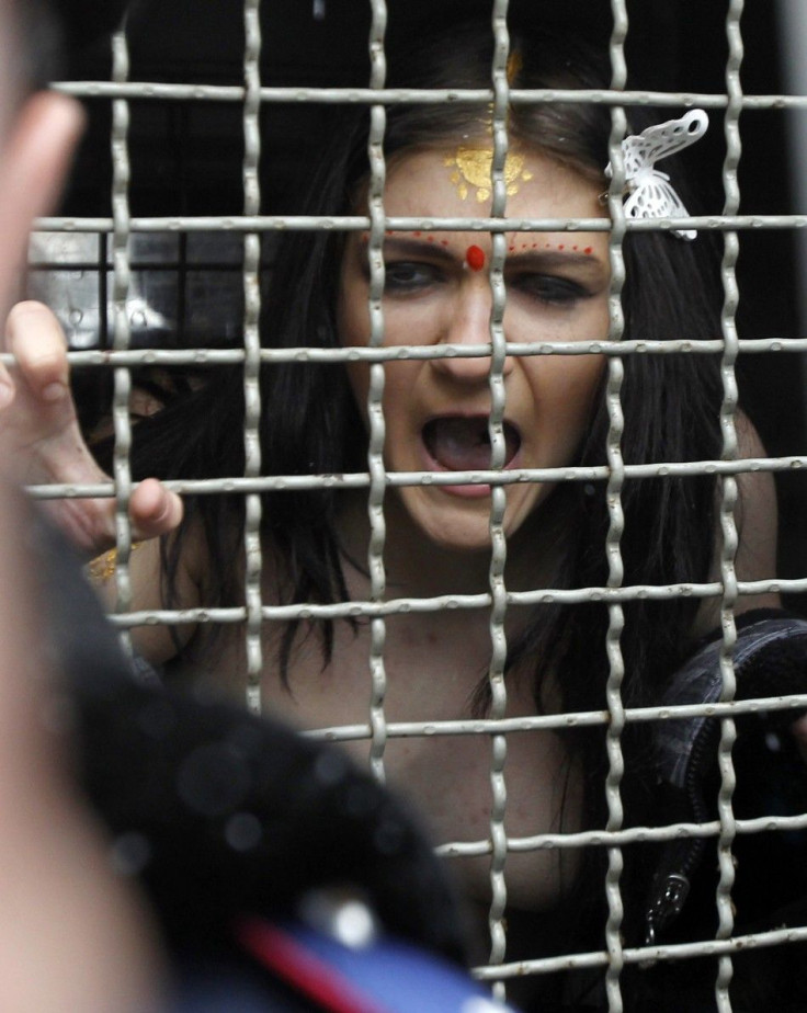 A detained activist from women&#039;s rights group Femen shouts from a police van during a protest in front of the residence of the Indian ambassador in Kiev