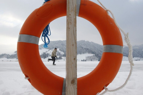 A man skates on the frozen lake Sihl (Sihlsee) past a life buoy on a freezing cold afternoon, outside Euthal, near Einsiedeln, February 4, 2012.