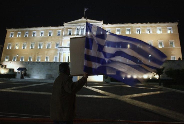 An anti-government protester holds a Greek flag as he shouts slogans against Greek Premier George Papandreou and his lawmakers in front of the parliament during a debate prior to a vote of confidence in Athens November 3, 2011.